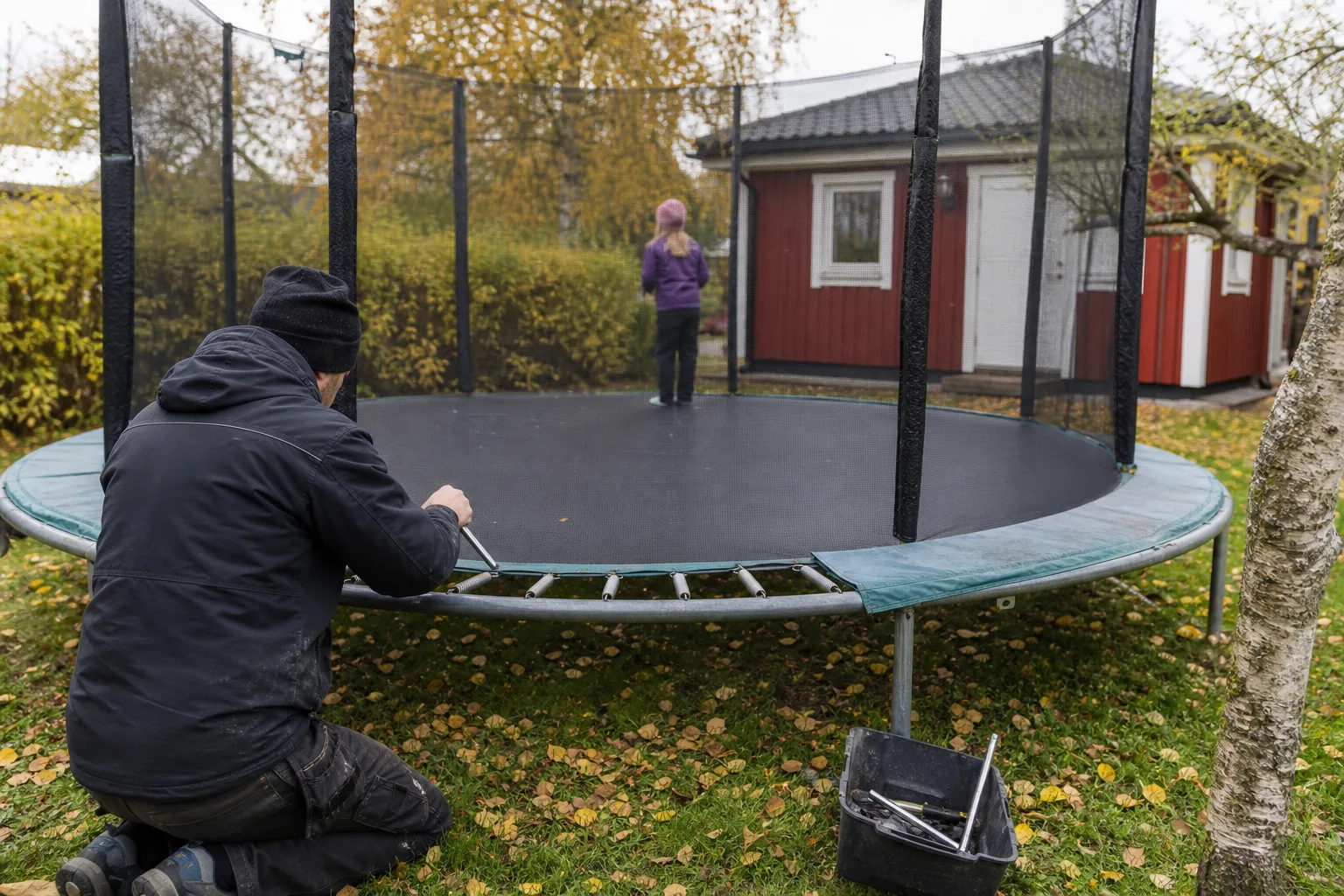 En förälder undersöker skyddsnätet och ramen på en äldre studsmatta